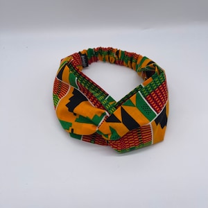 Puede incluir: Una diadema con nudo de diseño amarillo, verde, rojo y negro.