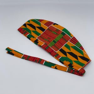 May include: A colorful surgical cap with a tie, featuring a geometric pattern in shades of red, yellow, green, and black.