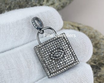 May include: A square, silver-toned pendant with a padlock design, encrusted with small, sparkling stones. The pendant has a loop at the top for a chain. The text "Fine Jewellers" is visible on the pendant.