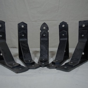 May include: Five black metal shelf brackets with decorative details. The brackets are all the same size and shape, and they have a slightly distressed finish.