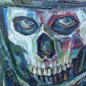 May include: A close-up of a painting depicting a skull with blue eyes and a white and red face. The skull is painted in a thick, textured style.