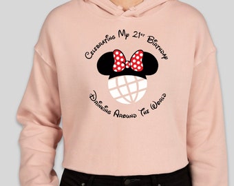 Könnte beinhalten: Hellrosa Kapuzenpullover mit einem Minnie-Maus-Ohren-Motiv, einer roten Schleife mit weißen Punkten und einem Globus-Design. Der Text lautet: "Celebrating My 21st Birthday Drinking Around The World."