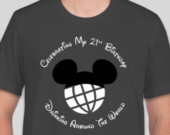 May include: A dark gray t-shirt with a white graphic of Mickey Mouse ears with a globe inside. The text "Celebrating My 21st Birthday Drinking Around The World" is written around the graphic.