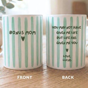 May include: White ceramic mug with vertical mint green stripes. The front of the mug reads "BONUS MOM" with a heart. The back of the mug has a message: "You may not have given me life but life has given me you" with a heart and "Love, Lucas."