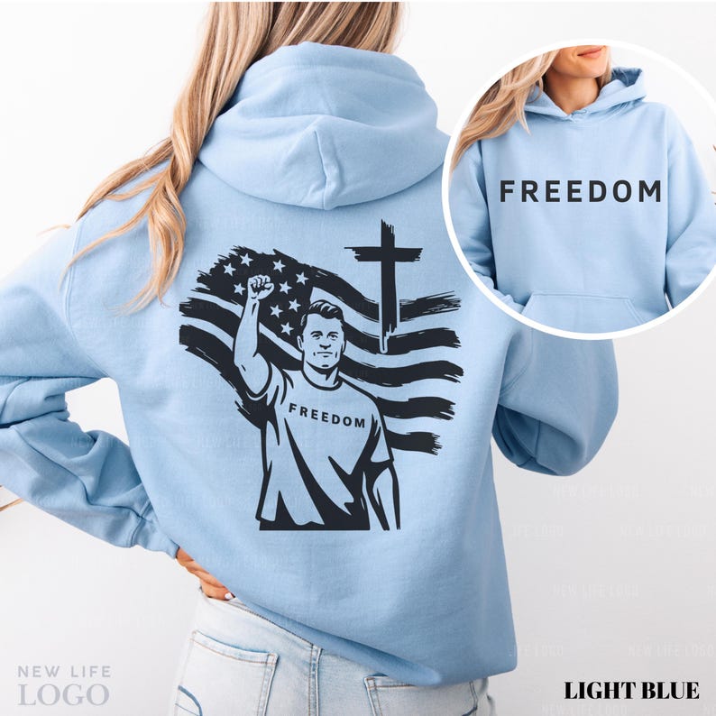 May include: Light blue hoodie with the word "FREEDOM" printed on the front and back. The back features a black and white graphic of a man with a raised fist, an American flag, and a cross. The hoodie is a light blue color.