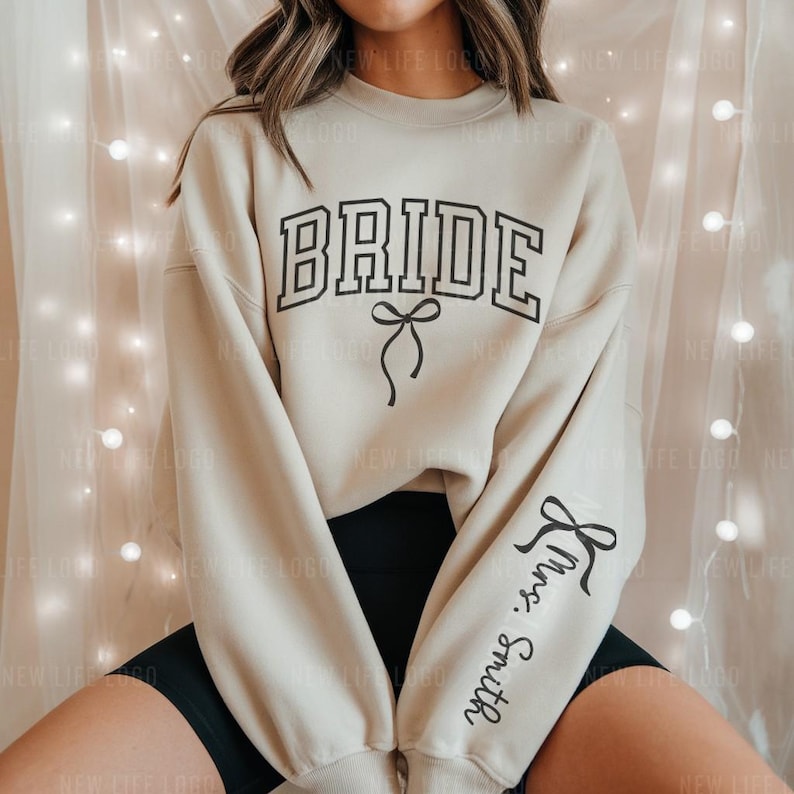 sand color Bride Sweatshirt with black Bow and the Custom Mrs. Last Name on sleeve. Perfect for an engagement.