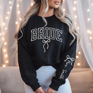 Black Bride Sweatshirt with white Bow and the Custom Mrs. Last Name on sleeve. Perfect for an engagement.