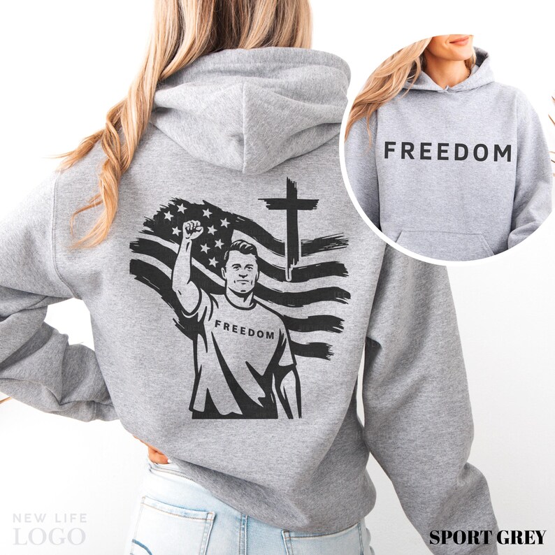 May include: Sport grey hoodie with a black graphic on the back featuring a man raising his fist in front of an American flag and a cross. The word "FREEDOM" is printed on the shirt and the hood.