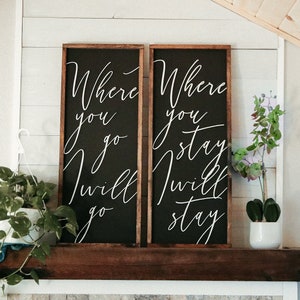 May include: Two black wooden signs with white calligraphy. The left sign reads "Where you go I will go". The right sign reads "Where you stay I will stay".