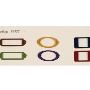 May include: Six different colored label holders, two rectangular and four oval. The label holders are brown, green, yellow, purple, blue, and red.