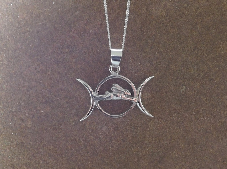 May include: Silver pendant necklace featuring a triple moon symbol with a stylized hare or rabbit inside the circle.