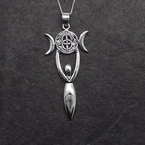 May include: Silver pendant necklace featuring a stylized female figure holding a triple moon symbol with a Celtic knot design. The pendant is on a silver chain.