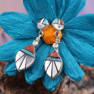 May include: A pair of silver dangle earrings with turquoise, red, and white inlay. The earrings are shaped like teardrops and have a small round bead at the top.