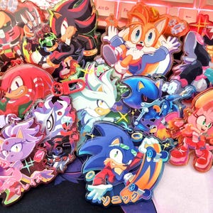 Könnte beinhalten: Eine Sammlung farbenfroher Charakter-Pins mit verschiedenen Charakteren aus dem Sonic the Hedgehog-Franchise. Die Pins zeigen Charaktere wie Sonic, Tails, Knuckles und andere, mit leuchtenden Farben und detaillierten Designs.
