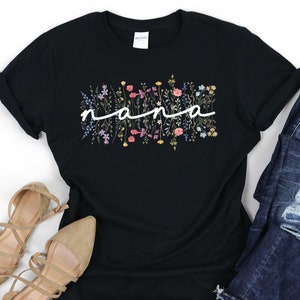May include: Black t-shirt featuring a floral design and the word "nana" in white script.