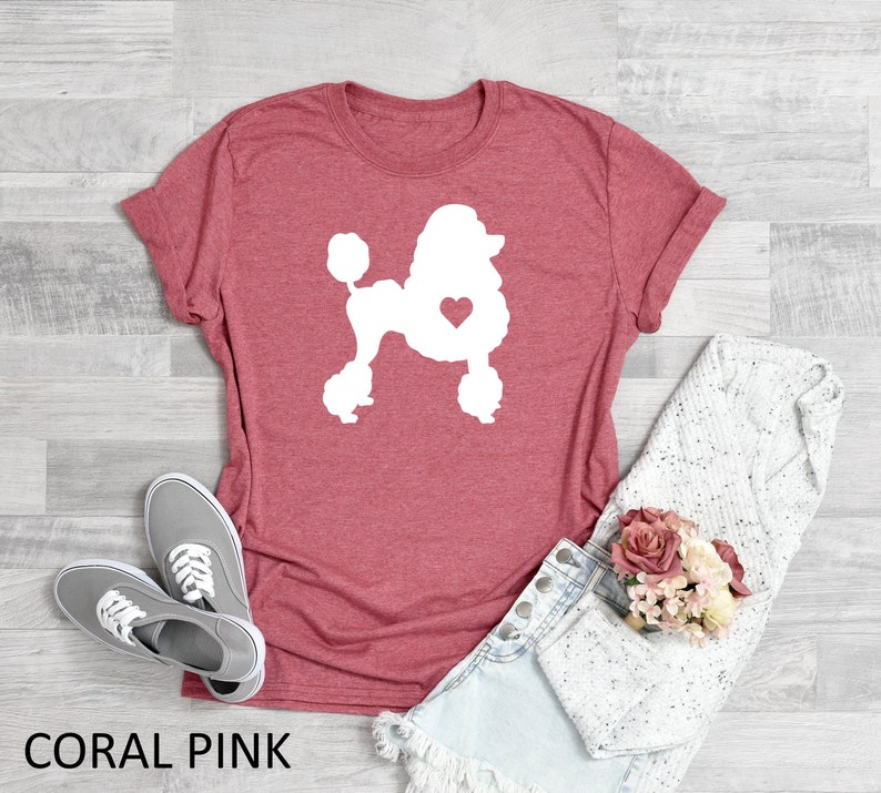 Puede incluir: Camiseta rosa coral con una silueta blanca de un caniche con un coraz&oacute;n en el pecho. El texto "CORAL PINK" est&aacute; en la parte inferior de la imagen.