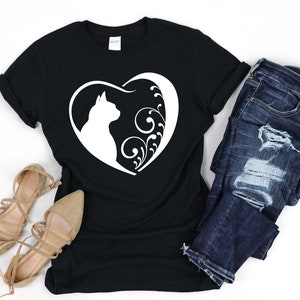 May include: Black t-shirt with a white silhouette of a cat inside a heart with floral designs.