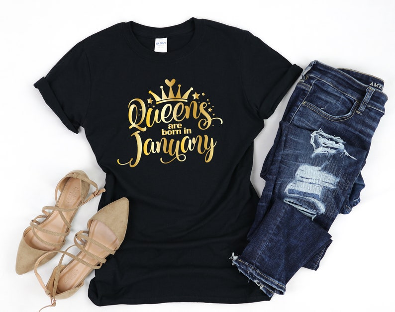 May include: Black t-shirt with gold lettering that says "Queens are born in January" with a gold crown above the text.