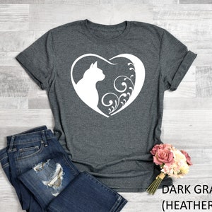 May include: Dark gray heather t-shirt with a white silhouette of a cat inside a heart with floral designs.