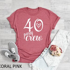 May include: Coral pink t-shirt with white text that says "40 party crew" with a small heart next to the 40.