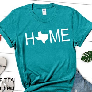 May include: Teal t-shirt with the word "HOME" in white text, with the state of Texas replacing the "O".