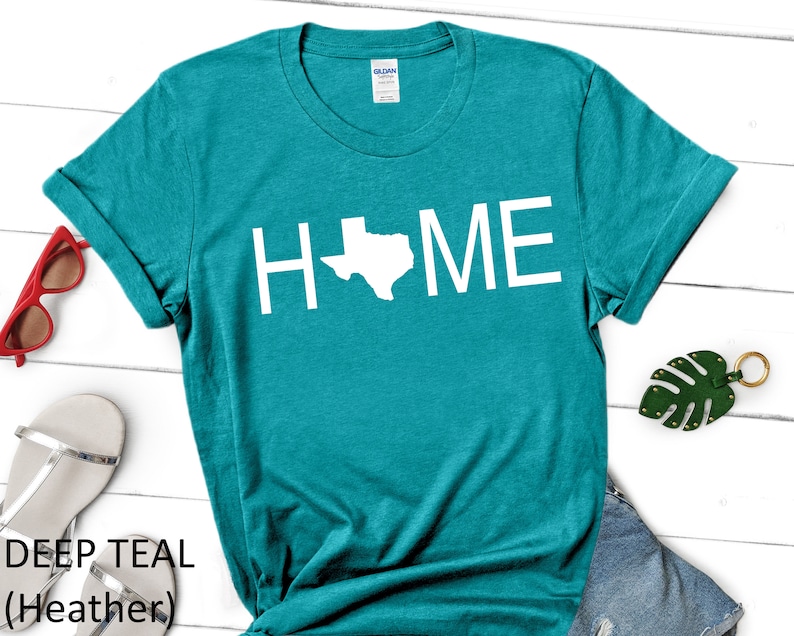 May include: Teal t-shirt with the word "HOME" in white text, with the state of Texas replacing the "O".