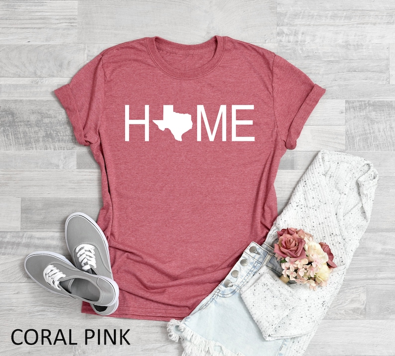 May include: Coral pink t-shirt with the word "HOME" in white text with the outline of the state of Texas replacing the "O".