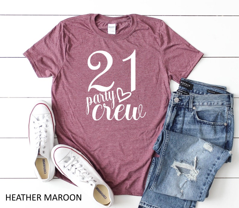May include: Heather maroon t-shirt with the text "21 party crew" in white. The shirt is paired with blue jeans and white sneakers. The image also includes the text "HEATHER MAROON".