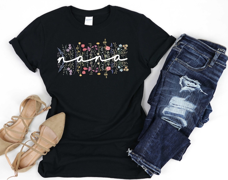 May include: Black t-shirt featuring a floral design and the word "nana" in white script.