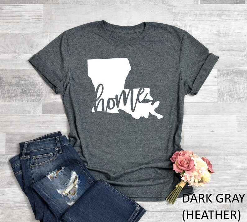 May include: Dark gray heather t-shirt with a white outline of the state of Louisiana and the word "home" written inside the state.