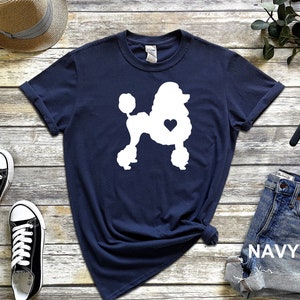 Puede incluir: Una camiseta azul marino con una silueta blanca de un caniche con un coraz&oacute;n en el pecho. La camiseta est&aacute; hecha de un material suave y c&oacute;modo y es perfecta para el uso diario.