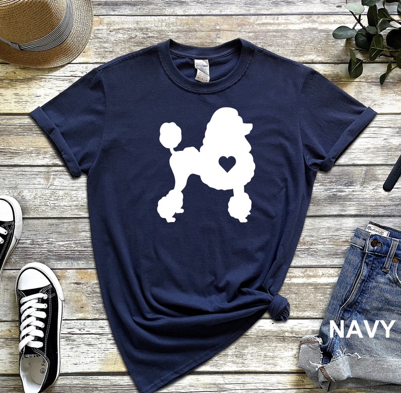 Puede incluir: Una camiseta azul marino con una silueta blanca de un caniche con un coraz&oacute;n en el pecho. La camiseta est&aacute; hecha de un material suave y c&oacute;modo y es perfecta para el uso diario.