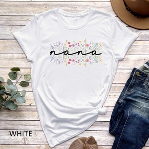 May include: White t-shirt with a floral design and the word "nana" in black lettering.