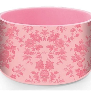 Puede incluir: Un contenedor de almacenamiento redondo de color rosa con un patrón floral. El contenedor tiene una tapa rosa.