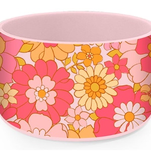 Puede incluir: Contenedor cilíndrico con estampado floral rosa y naranja. El estampado presenta flores grandes y pequeñas en un estilo retro.