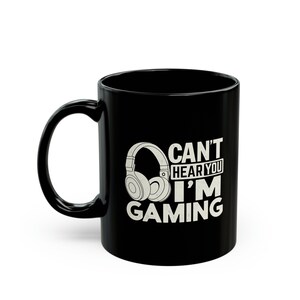 May include: Black ceramic mug with a white graphic of headphones and the text "CAN'T HEAR YOU I'M GAMING". The mug has a curved handle and a glossy finish. A perfect gift for gamers.