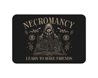 May include: Black rectangular mousepad with a beige illustration. The illustration features a hooded skeleton reading a book with the word "NECROMANCY" above and "LEARN TO MAKE FRIENDS" below. The design includes snakes, eyes, and candles.