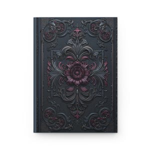 Può includere: Un diario con copertina rigida con una copertina grigio scuro con un ornato motivo floreale in rilievo nei toni del grigio e del bordeaux. La copertina ha un aspetto strutturato e il design è simmetrico, con un grande fiore al centro.