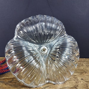 May include: A clear glass dish with a three-leaf clover design. The dish has a textured, ribbed surface and a small metal knob in the center.