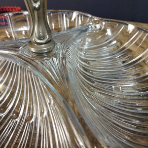 May include: A clear glass serving dish with three sections and a silver handle. The dish has a decorative, ribbed pattern.