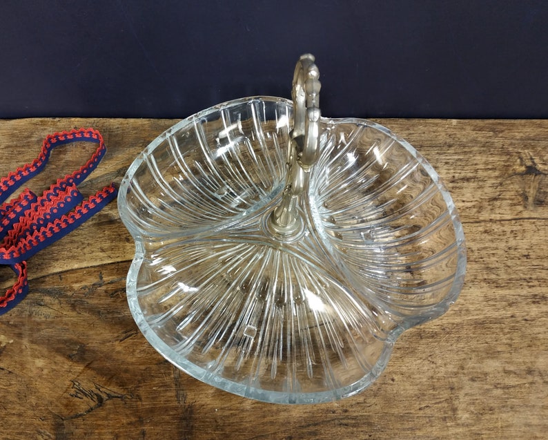 May include: A clear glass serving dish with three sections and a silver handle. The dish has a decorative, ribbed pattern.