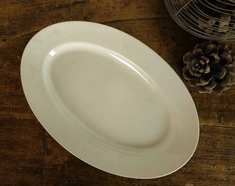 May include: A white oval serving platter with a slightly raised rim. The platter is made of ceramic and has a smooth, glossy finish.