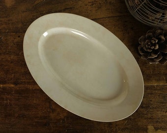 May include: A white oval serving platter with a slightly raised rim. The platter is made of ceramic and has a smooth, glossy finish.