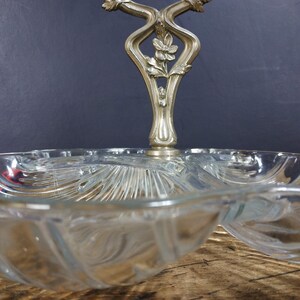 May include: A clear glass serving dish with a decorative silver handle. The dish has three sections and is perfect for serving snacks or appetizers.