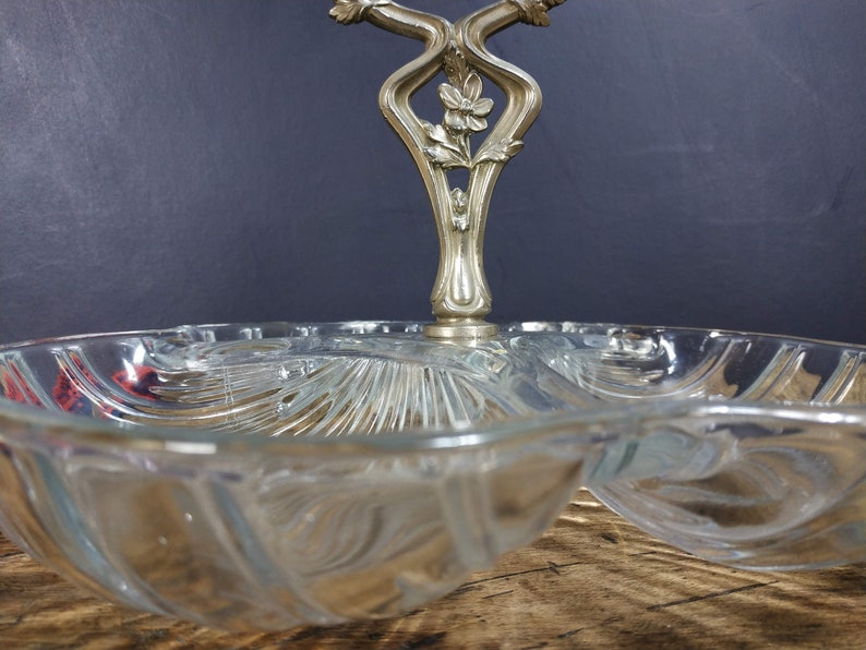 May include: A clear glass serving dish with a decorative silver handle. The dish has three sections and is perfect for serving snacks or appetizers.