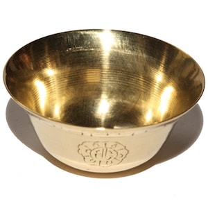 Puede incluir: Un pequeño cuenco de latón de color dorado con un diseño decorativo en el fondo. El cuenco es liso y brillante.