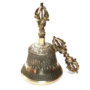 May include: A gold-colored bell with intricate designs and a matching hand-held striker. The bell is used in Buddhist rituals.