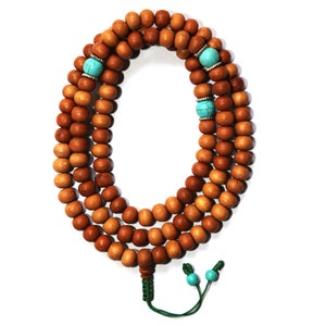 May include: A brown wooden mala bead necklace with turquoise beads and a green tassel.
