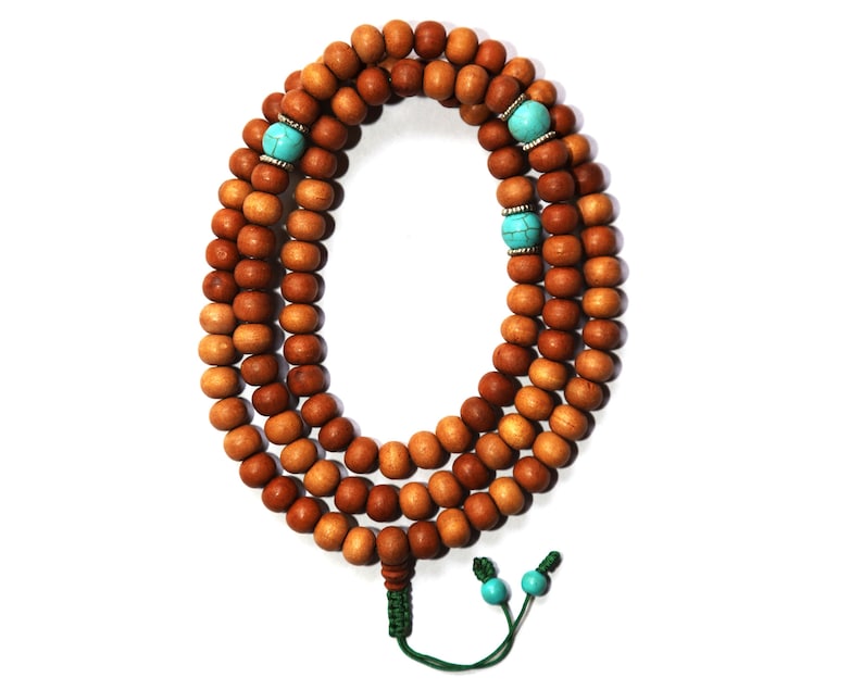 May include: A brown wooden mala bead necklace with turquoise beads and a green tassel.
