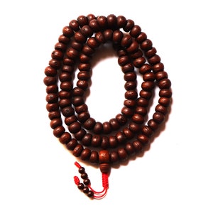 May include: A brown wooden mala bead necklace with 108 beads and a red tassel. The beads are round and have a smooth finish.